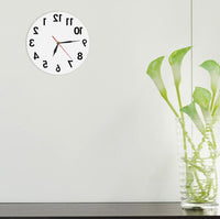 Horloge inversée ronde 30 cm blanche sens contraire design avec vase et fleurs sur un meublee