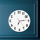 Horloge inversée ronde 30 cm blanche design antihoraire fixée sur un mur bleu