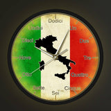 Horloge murale ronde avec un cadre noir. Le cadran représente le drapeau italien tricolore (vert, blanc, rouge) avec une texture vieillie. Au centre, une silhouette noire de la carte de l'Italie. Les aiguilles sont argentées. Les heures sont écrites en toutes lettres en italien : Dodici, Un, Due, Tre, Quattro, Cinque, Sei, Sette, Otto, Nove, Dieci, Undici avec LED