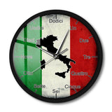 Vue de face d'une horloge murale ronde avec un cadre noir, posée sur un fond blanc avec une ombre portée. Le cadran présente le drapeau italien, la carte noire de l'Italie et les heures écrites en toutes lettres en italien.