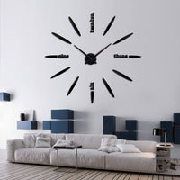 Horloge géante adhésive modèle Luna noire installée dans un salon moderne avec canapé gris.