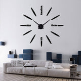 Horloge géante adhésive modèle Luna noire installée dans un salon moderne avec canapé gris.
